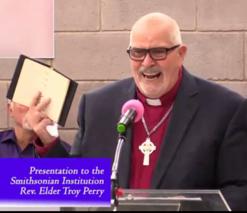 Troy Perry giving prayer book to Smithsonian